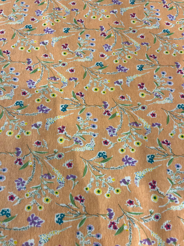 Floral flannel-yellow, fuschia , teal, and lavender flowers on green stems featured on a peach background.