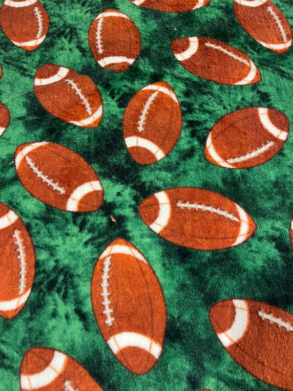 Footballs on turf whisper fleece.   100% polyester, 60” wide and $9.99 per yd.